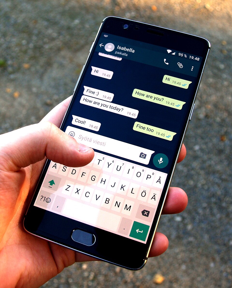 Una mano sostiene un teléfono con una conversación de WhatsApp